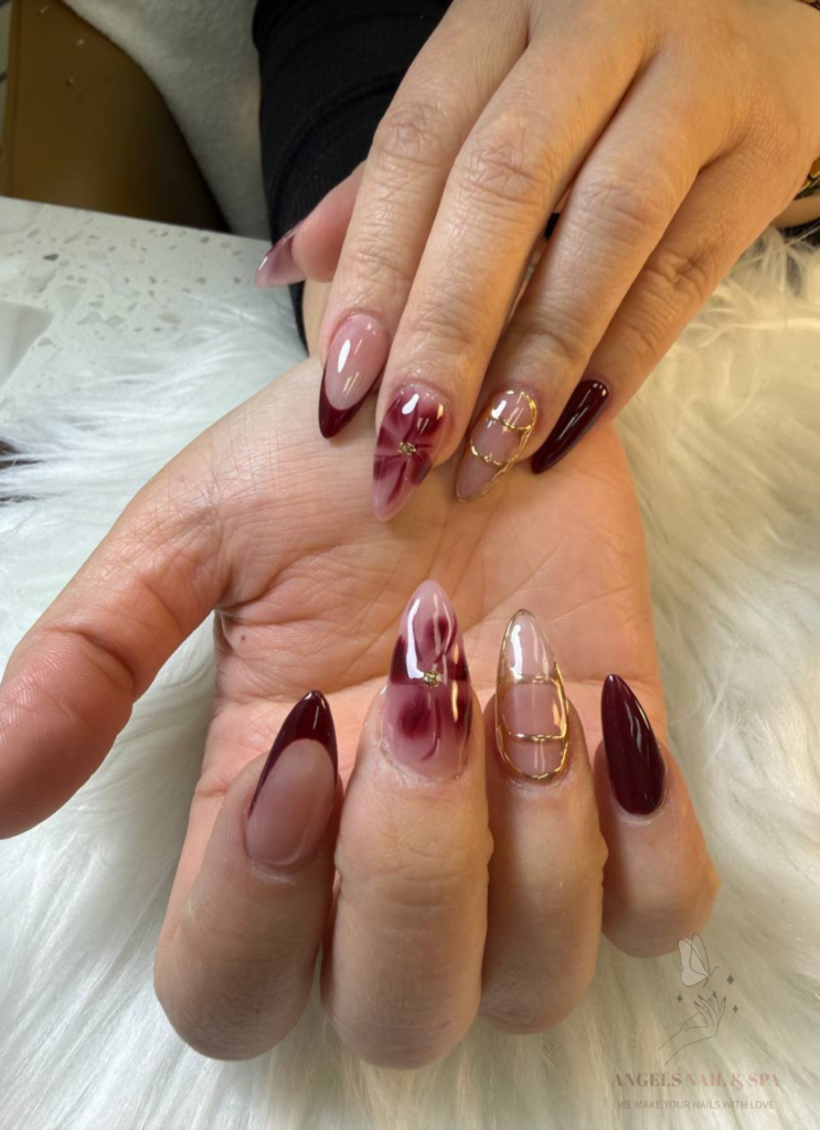 trendy nail design with wine red marble and gold accents in Yarmouth